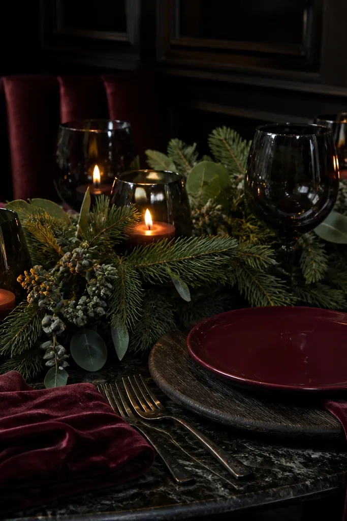 Oxblood floral centerpieces with dark green foliage and glowing amber candlelight