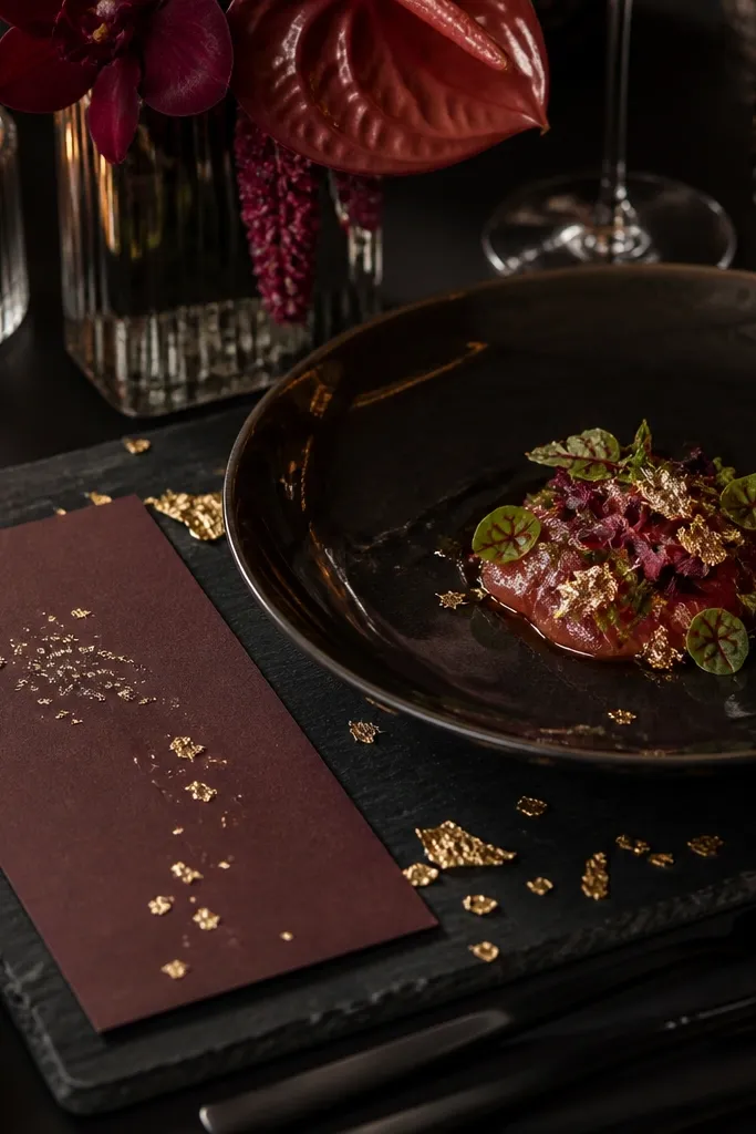 Smoky burgundy linens with black tea floral blooms and gold leaf place card accents